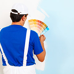 Man comparing paint samples to wall color